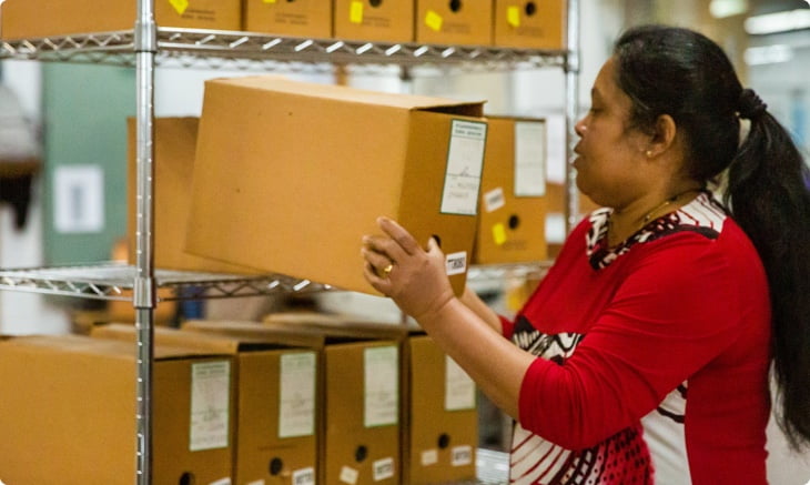 Records Scanning manager, Kani, is putting a box on a shelf