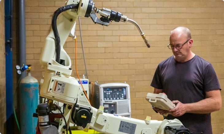 Tool maker David is working with a welding robot