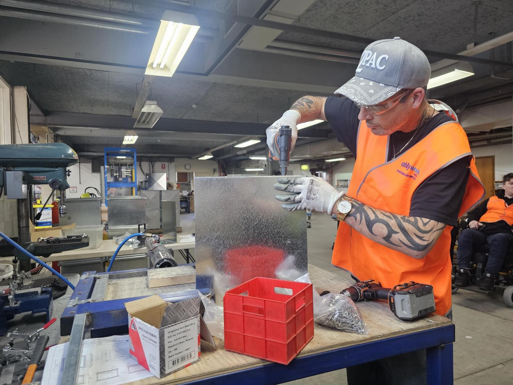 An employee is working in manufacturing, drilling screws into a metal frame.