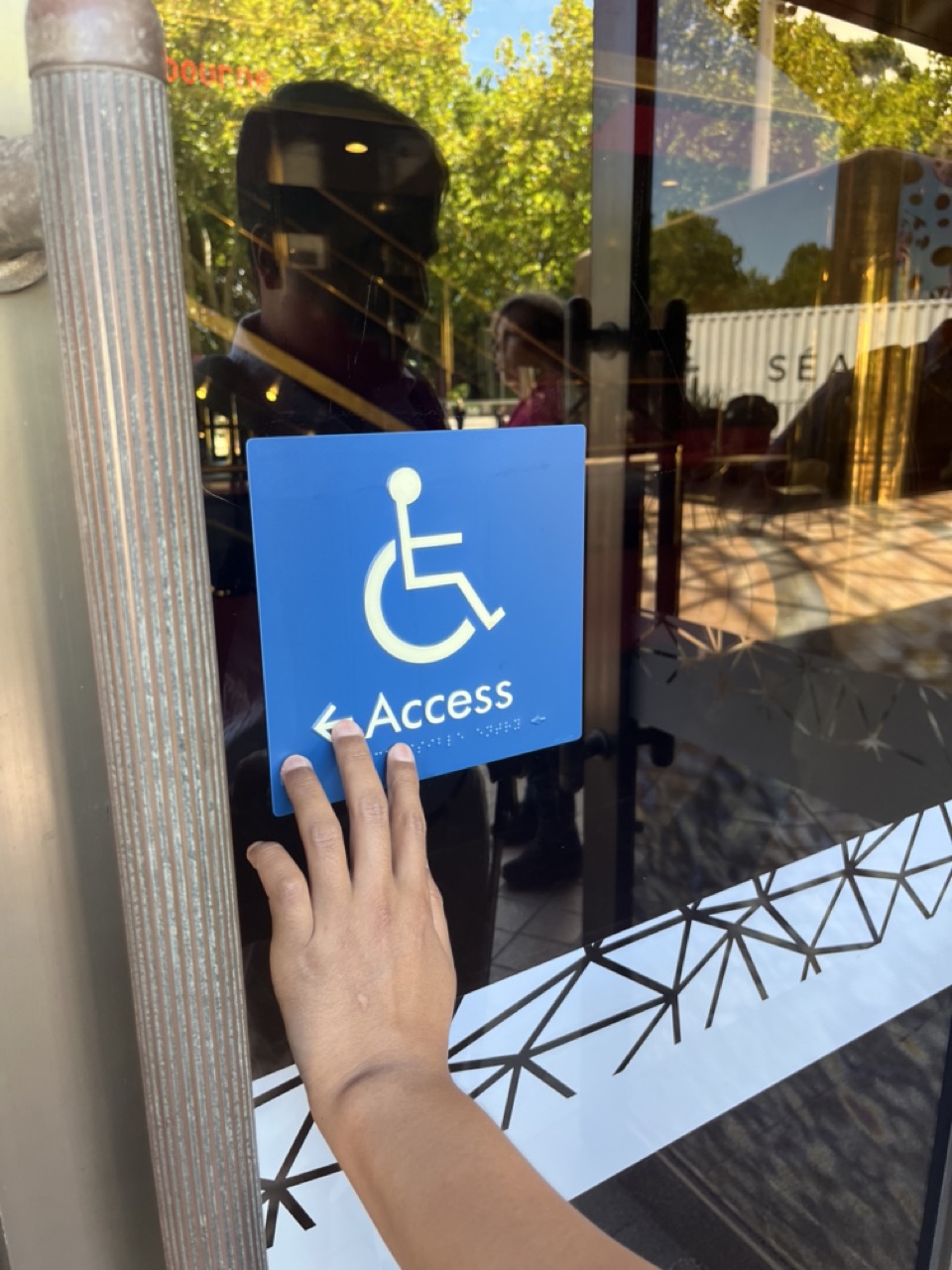 a hand is feeling a disability access sign for braille