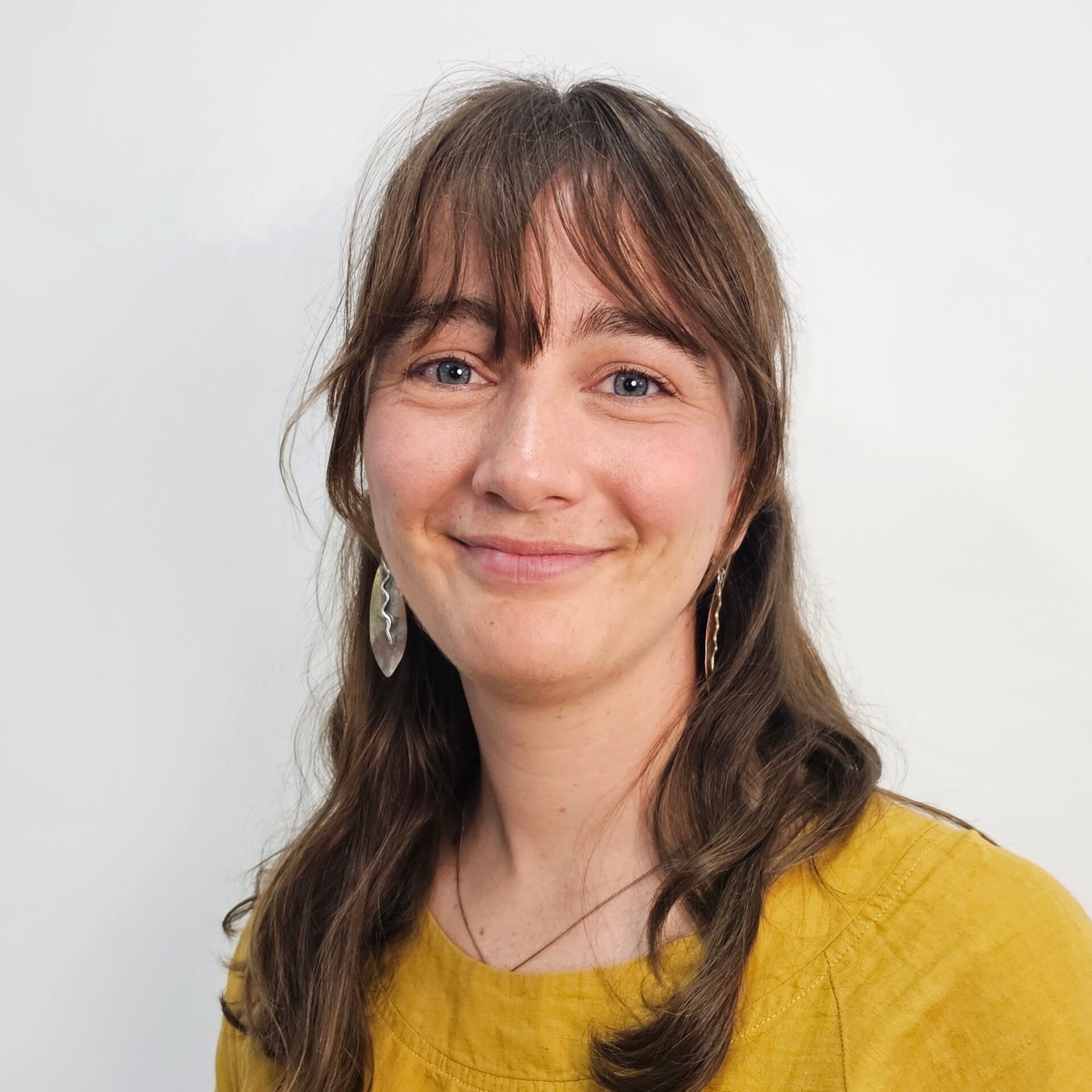 Annaliese has long dark hair and is wearing a brightly coloured shirt. She is smiling.